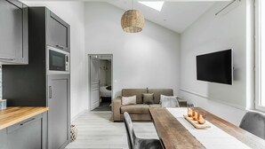 A modern kitchen with dark cabinets, a wooden countertop, and a built-in microwave.