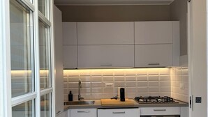 A modern kitchen with white cabinets, a gas stove, a built-in oven, and a large window with frosted glass. - Inside Lucca  Walls, Historic Home,  private Garden, Terrace (Lucca)