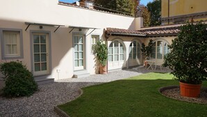 A courtyard with a lawn, potted plants, and a seating area with a table and chairs. - Inside Lucca  Walls, Historic Home,  private Garden, Terrace (Lucca)