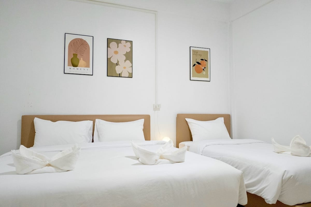 A hotel room with two beds, white linens, and three framed artworks on the wall.