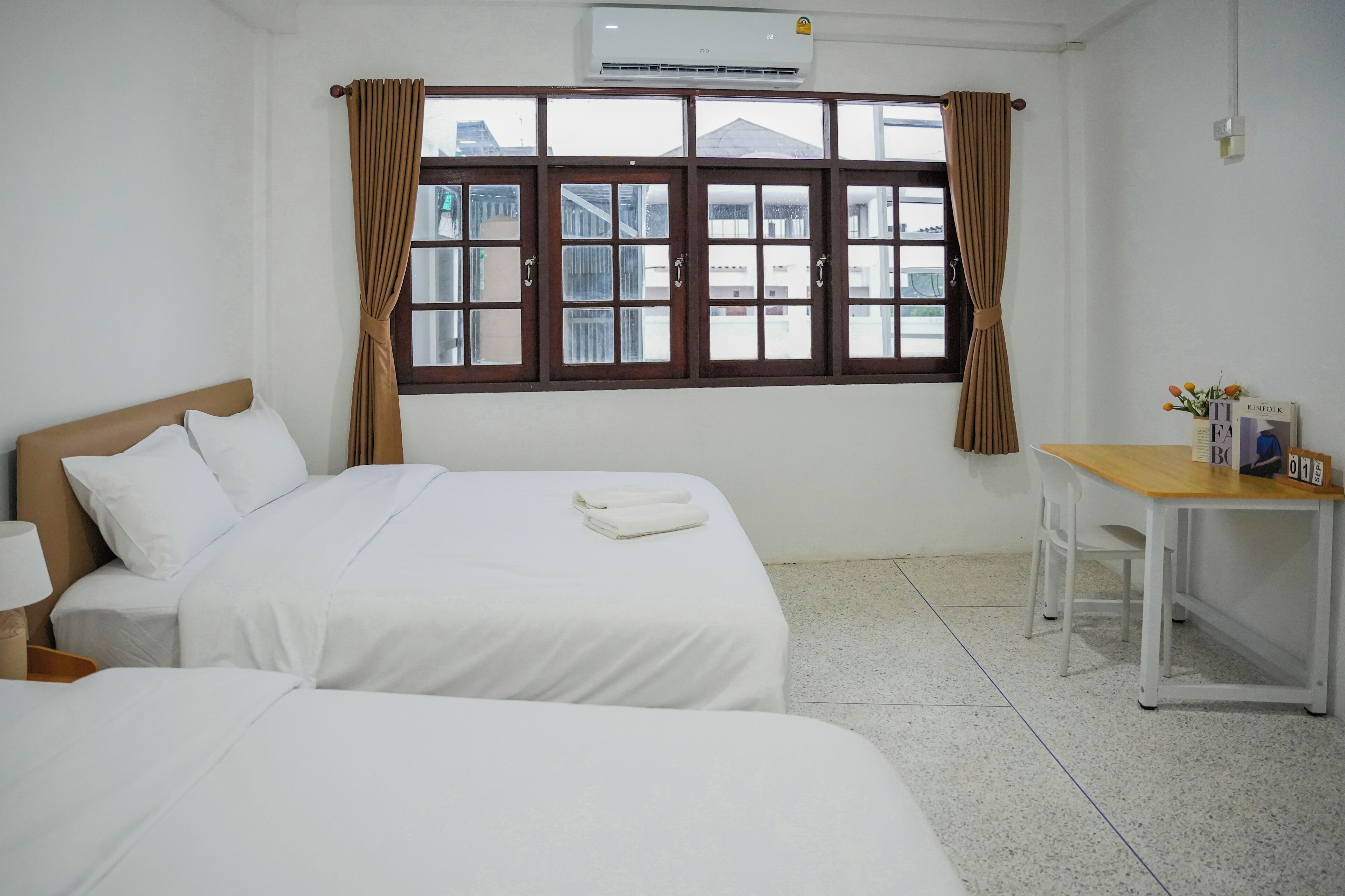 A hotel room with two beds, a desk, and a window with curtains.