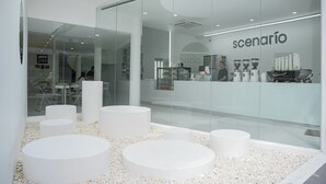 Un intérieur moderne avec des murs en verre, des sièges circulaires blancs et un espace dédié aux machines à café.