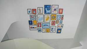 Un mur orné de plusieurs œuvres d’art encadrées, disposées selon un motif en grille.