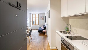 Una cocina moderna con horno integrado, un lavamanos con escurreplatos y una zona de comedor con mesa y sillas.