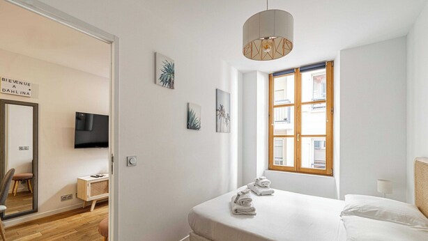 Un dormitorio moderno con una cama, un televisor, una ventana y obras de arte en la pared.