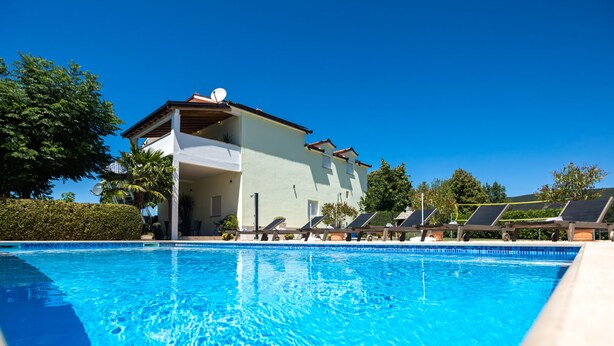A swimming pool with lounge chairs and a building in the background. - Green Oasis by Interhome (Imotski)