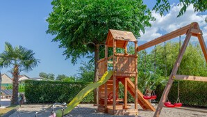 A wooden playground with a slide and swings, surrounded by trees and a gravel area. - Green Oasis by Interhome (Imotski)