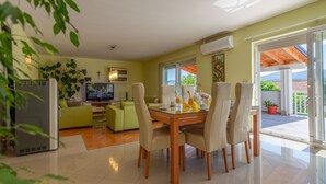 A modern living room with a dining area, a television, and a balcony with a view. - Green Oasis by Interhome (Imotski)