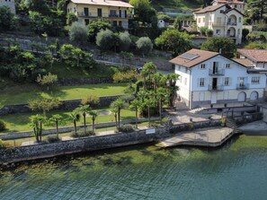 A coastal property with a white building, a stone wall, and a small dock.