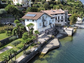 Un edificio de dos pisos con techo de tejas, un balcón y un pequeño muelle que se adentra en el agua.