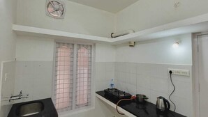 Eine kleine Küche mit Spüle, einem Fenster mit Gitterstäben, einem Ventilator und einem Herd.