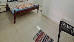 Ein Schlafzimmer mit einem Bett, einem Deckenventilator, einem Fenster mit Vorhängen und einem kleinen Teppich.