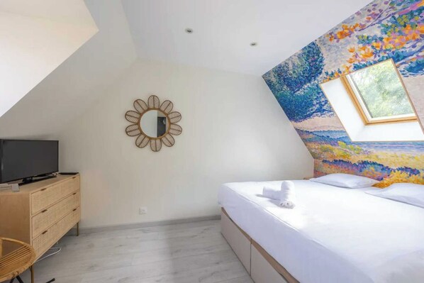 Un dormitorio con cama, cómoda, televisor y espejo montado en la pared.