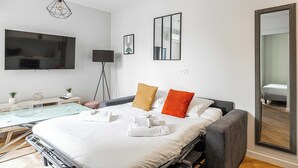Ein modernes Hotelzimmer mit Bett, Fernseher, Schreibtisch und einem großen Spiegel.