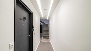 Ein Flur mit einer schwarzen Tür mit der Aufschrift "01", einer Treppe und einem gemusterten Teppich.