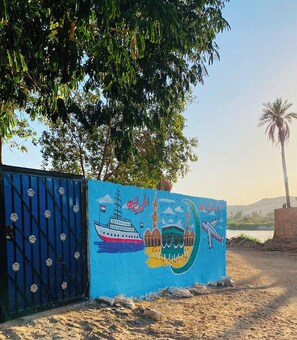 Un portal blau amb un mural que representa una mesquita, un vaixell i una palmera.