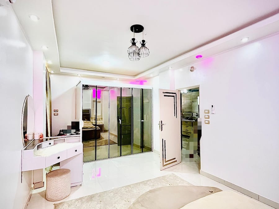 A modern bedroom with a large bed, a vanity with a mirror, and a walk-in closet.