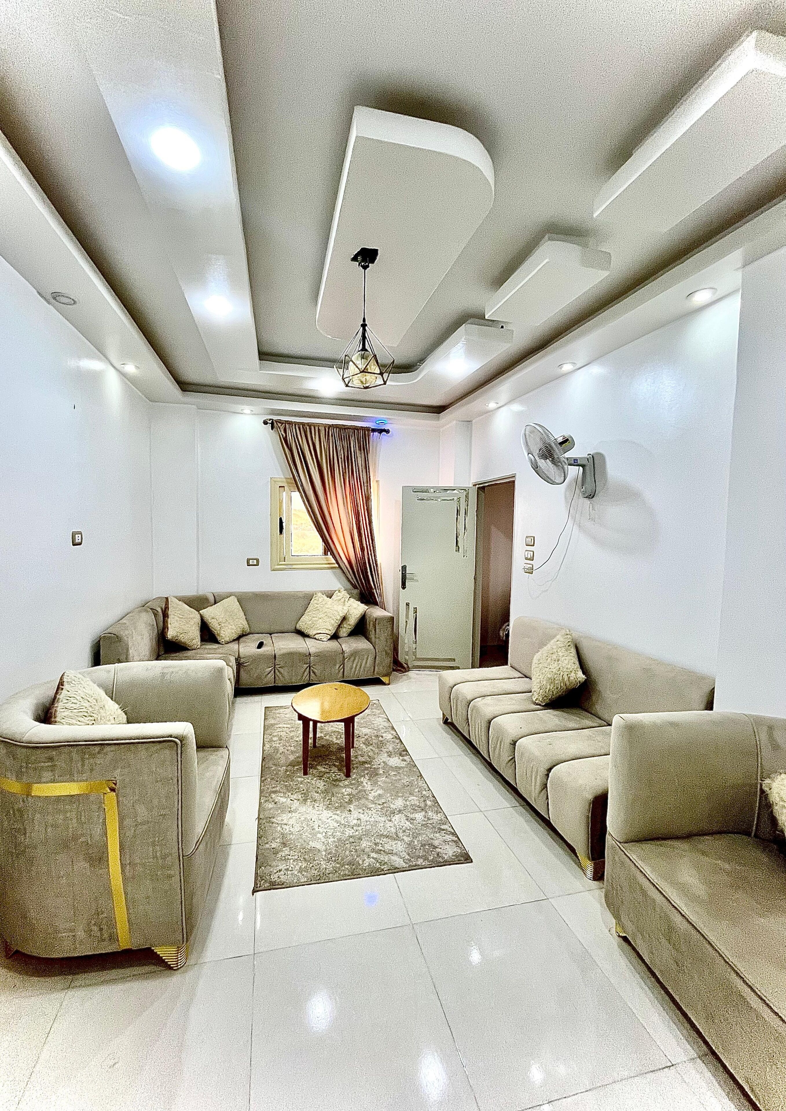 A modern living room with a sectional sofa, a coffee table, and a ceiling fan.