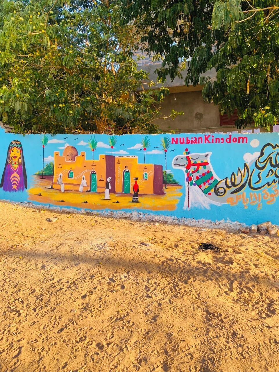 Un mural con un edificio tradicional, palmeras y un camello.