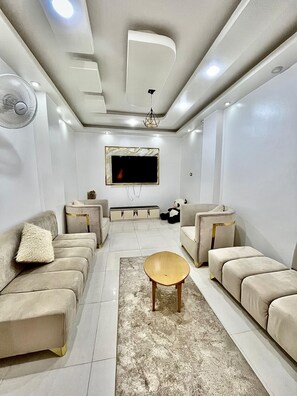 A modern living room with sofas, a coffee table, a TV, and a ceiling fan. - Nubian kingdom  (Aswan)