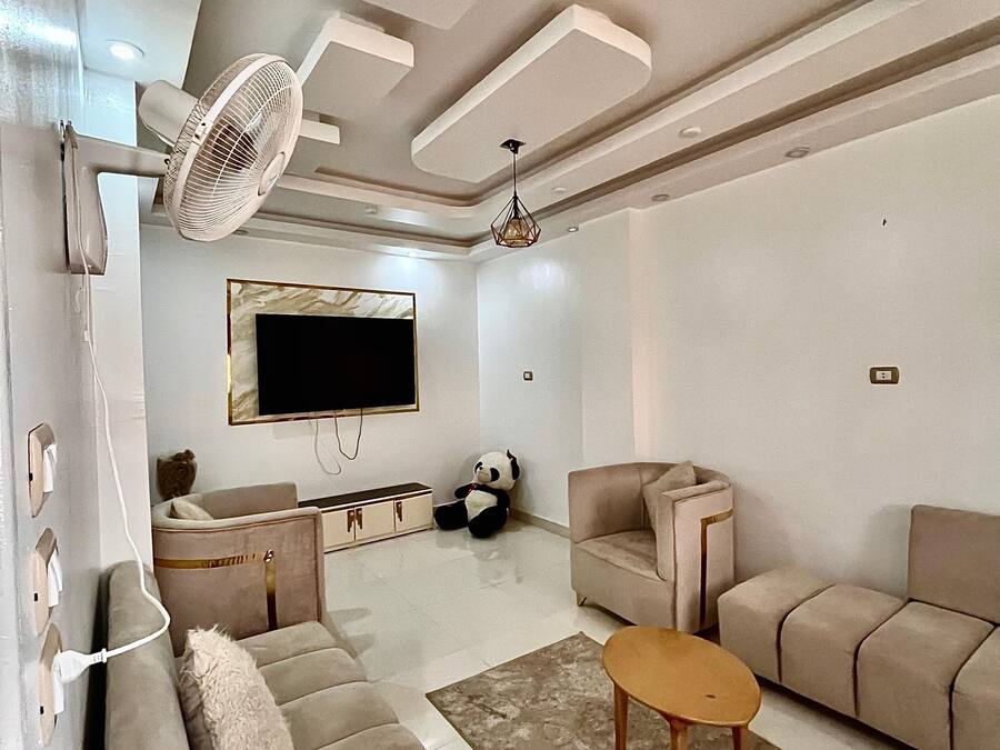 A modern living room with a sofa, a coffee table, a TV, and a fan.