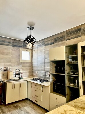 A kitchen with a gas stove, a sink, cabinets, and a decorative hanging light fixture. - Nubian kingdom  (Aswan)