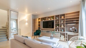 A modern living room with a sofa, a coffee table, a TV, and a built-in shelving unit with decorative items.