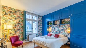 A bedroom with a bed, a red chair, and blue cabinets.
