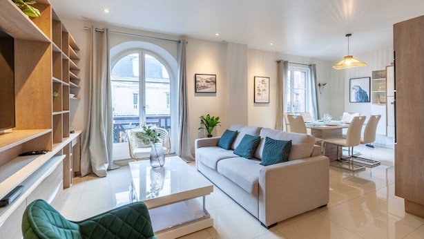 A modern living room with a sofa, coffee table, and a dining area with a table and chairs.