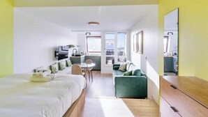 Quarto de hotel moderno com uma cama, um sofá verde, uma escrivaninha e um espaço para refeições.