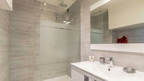Un bagno moderno con doccia vetro, un mobile lavabo bianco con specchio e una decorazione a forma di rosa rossa sul muro.