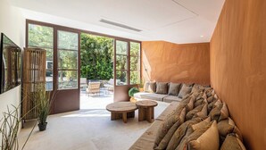 Un salon moderne doté de grandes fenêtres, d’un mur d’accent en bois et d’un coin salon confortable.