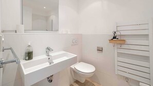 A modern bathroom with a white sink, toilet, and a mirror above the sink.