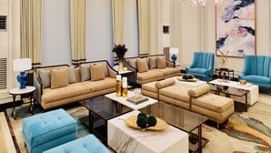 A spacious living room with a large sofa set, blue ottomans, and a chandelier. - Saint Honore & Saint Dominique (Iloilo)