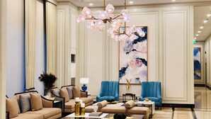 A spacious lobby with a high ceiling, a chandelier, and a large abstract painting. - Saint Honore & Saint Dominique (Iloilo)