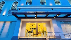 A hotel entrance with a blue facade, multiple balconies, and a well-lit entrance area. - Saint Honore & Saint Dominique (Iloilo)