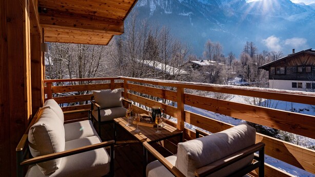 Une terrasse en bois offrant une vue sur des montagnes enneigées et un ciel dégagé.