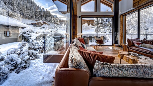 A cozy, modern living room with large windows overlooking a snowy mountain landscape. - Serviced Luxury Chalet with 10m Indoor Pool (Chamonix-Mont-Blanc)