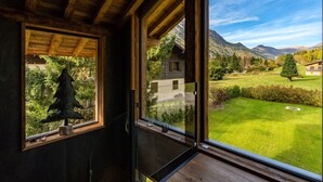 A room with large windows offering a view of a mountainous landscape and a well-maintained lawn. - Serviced Luxury Chalet with 10m Indoor Pool (Chamonix-Mont-Blanc)