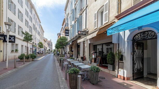 A street lined with cafes and shops, featuring outdoor seating and a clear sky. - Beautiful apartment - Croisette Gray Albion (Cannes)