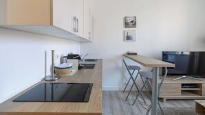 Eine moderne Küche mit Einbauherd, Spüle und Essbereich mit Fernseher und klappbaren Stühlen.