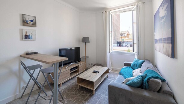 Ein modernes Wohnzimmer mit Fernseher, Esstisch und Sofa.
