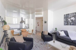 A modern living room with a sofa, armchairs, a coffee table, and a dining area with a table and chairs. - Elegant  flat in Cannes 2BR-4P (Cannes)