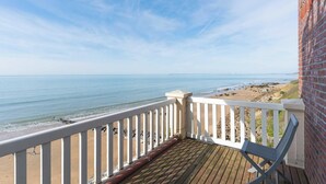 Une terrasse en bois avec une balustrade blanche donnant sur une plage.