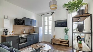 Een moderne woonkamer met een bank, salontafel en een aan de muur bevestigde televisie.