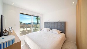 A modern bedroom with a large bed, a TV, and a balcony with outdoor furniture. - Sumptuous terrace apartment - Cannes - Sea view (Cannes)