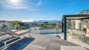 A rooftop terrace with lounge chairs, a dining area, and a view of the city and mountains. - Sumptuous terrace apartment - Cannes - Sea view (Cannes)