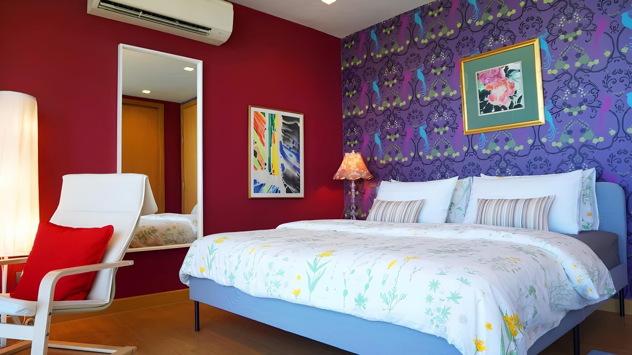 A bedroom with a bed, a chair, a mirror, and a wall with a floral pattern.