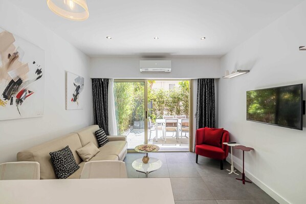 A modern living room with a sofa, a red chair, a small table, and artwork on the walls. - Standing flat 3P, 2 min from the Croisette (Cannes)