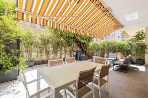 A covered outdoor dining area with a table and chairs, surrounded by potted plants and a climbing vine. - Standing flat 3P, 2 min from the Croisette (Cannes)